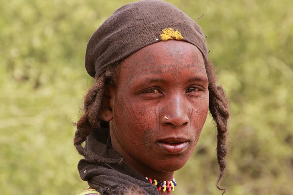 joven fulani con tatuajes en el rostro y dos trenzas enmarcando la cara